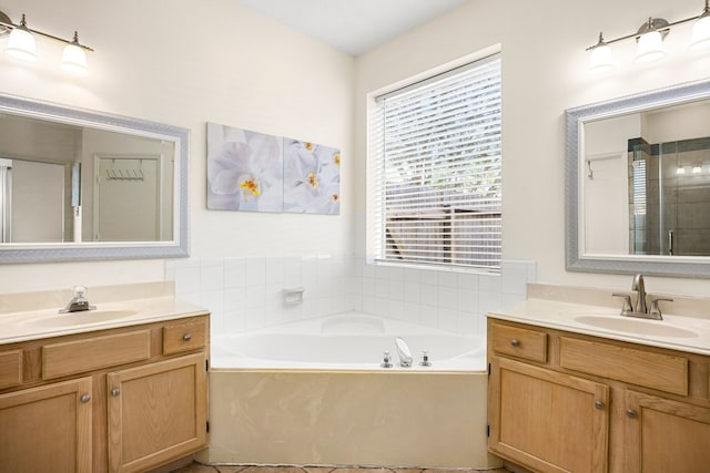 bathroom featuring a garden tub, two vanities, and a sink