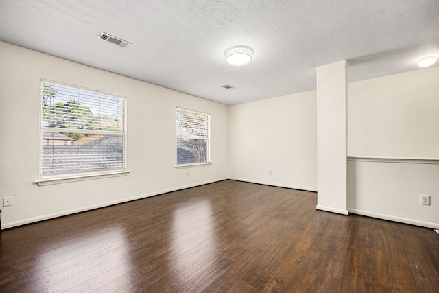 unfurnished room featuring a textured ceiling, dark wood-type flooring, visible vents, and baseboards