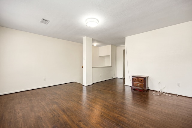 interior space featuring baseboards, a textured ceiling, visible vents, and dark wood-style flooring