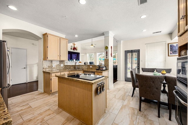 kitchen with stainless steel appliances, light brown cabinetry, a kitchen island, and visible vents