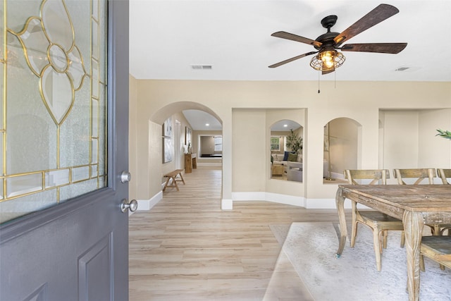 dining room featuring arched walkways, light wood-type flooring, visible vents, and baseboards