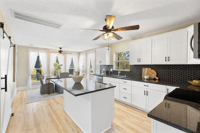 kitchen featuring a center island, visible vents, a barn door, appliances with stainless steel finishes, and white cabinets