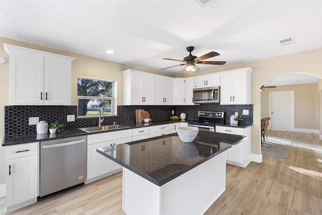 kitchen with appliances with stainless steel finishes, a sink, a center island, and white cabinets