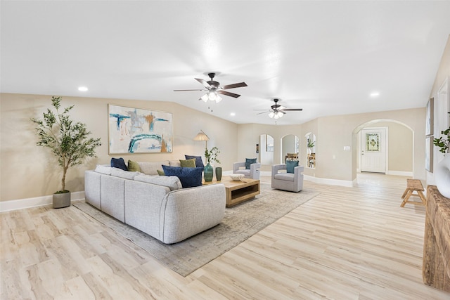 living room with arched walkways, recessed lighting, baseboards, and light wood-style floors