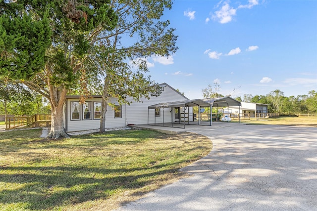 view of front facade featuring driveway, fence, and a front yard