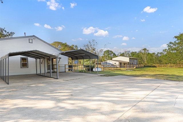 exterior space featuring driveway, a yard, fence, and a detached carport