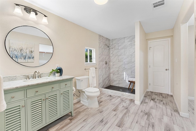 full bath featuring visible vents, tiled shower, toilet, and wood finished floors