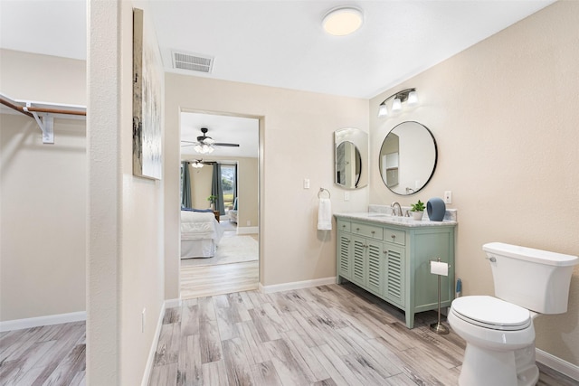 ensuite bathroom with visible vents, vanity, baseboards, and wood finished floors