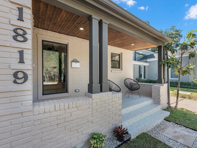 entrance to property featuring brick siding and a porch