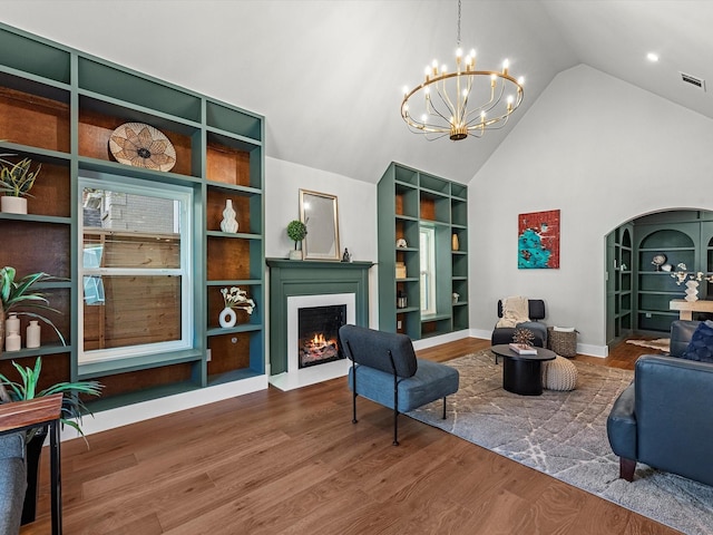 sitting room featuring arched walkways, wood finished floors, a fireplace with flush hearth, and visible vents