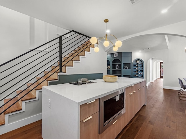 kitchen with dark wood-style floors, modern cabinets, a center island, built in microwave, and light countertops