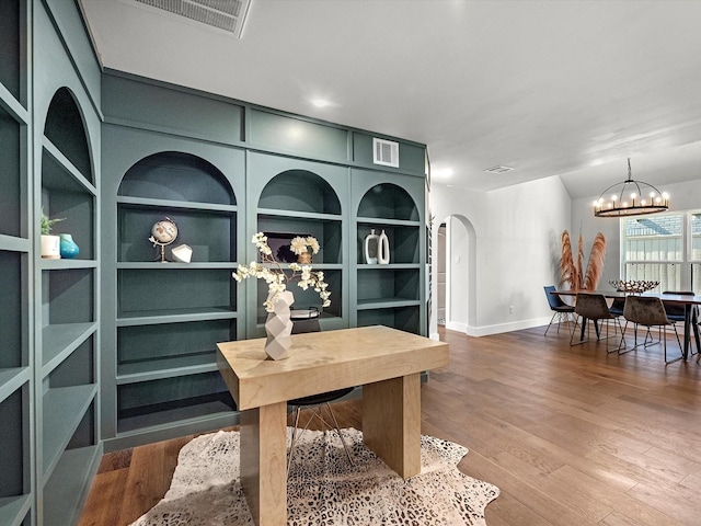 office area with visible vents, arched walkways, lofted ceiling, wood finished floors, and a notable chandelier