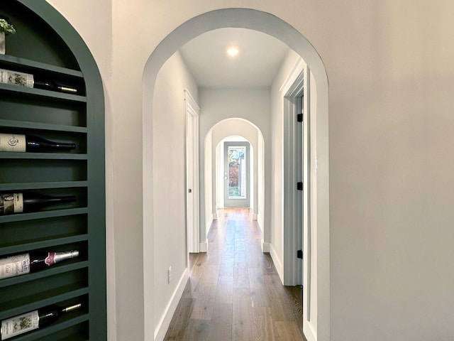 hall featuring built in shelves, baseboards, and wood finished floors