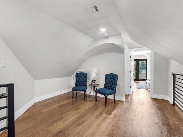 sitting room featuring visible vents, vaulted ceiling, and light wood finished floors