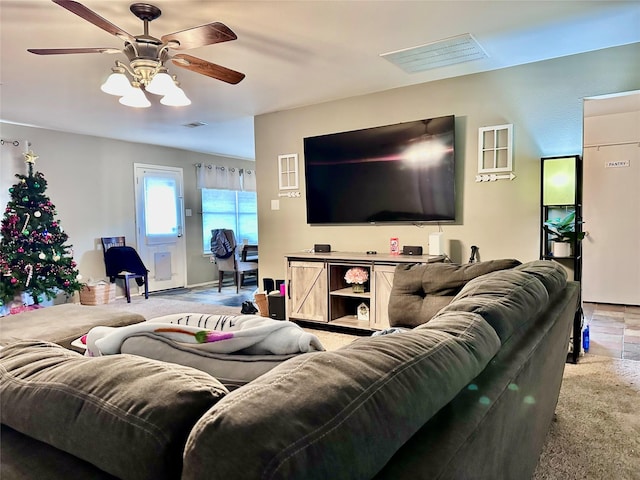 living area with ceiling fan, visible vents, and light colored carpet