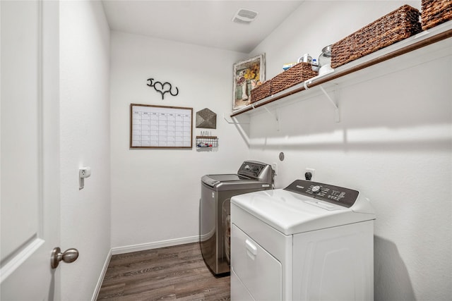 laundry area with laundry area, baseboards, visible vents, wood finished floors, and washer and dryer