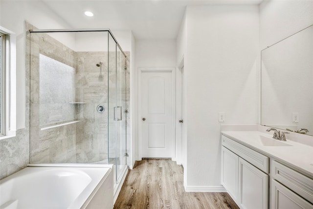 full bath featuring a garden tub, recessed lighting, wood finished floors, vanity, and a stall shower