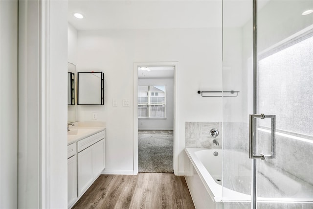 full bathroom with a garden tub, wood finished floors, vanity, and baseboards