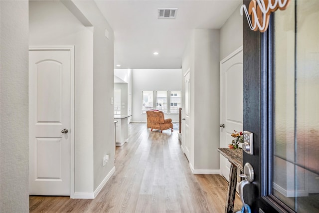 corridor with light wood-style flooring, visible vents, baseboards, and recessed lighting