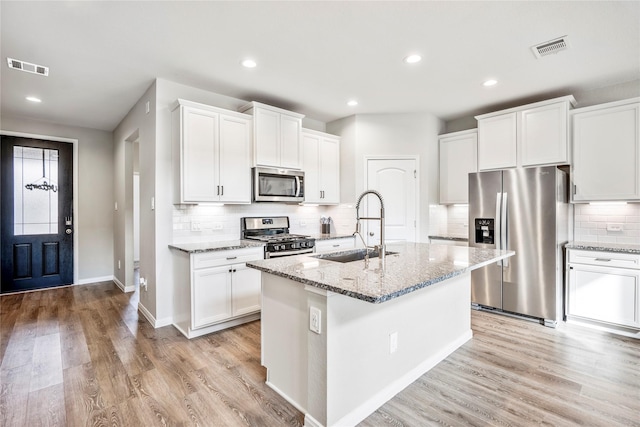 kitchen with a kitchen island with sink, a sink, visible vents, white cabinets, and appliances with stainless steel finishes