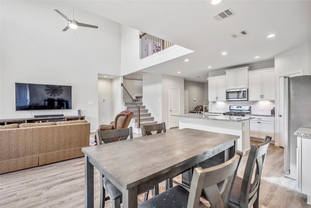 dining area featuring light wood-style floors, visible vents, and stairs