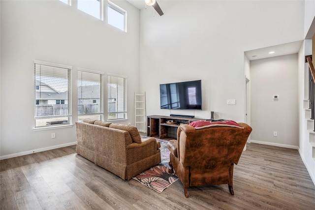 living room with a towering ceiling, baseboards, and wood finished floors