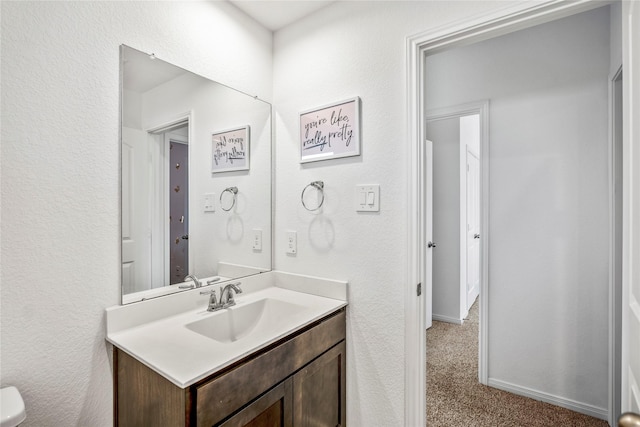 bathroom featuring a textured wall, vanity, and baseboards