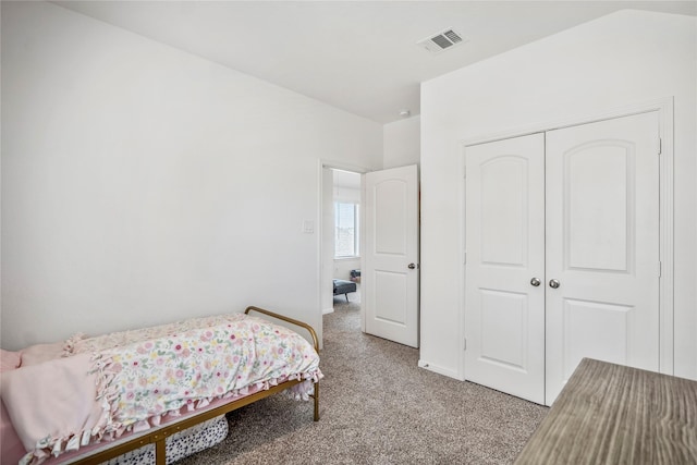 bedroom with a closet, visible vents, and light colored carpet