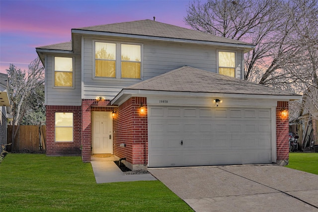 traditional-style house with concrete driveway, a lawn, an attached garage, fence, and brick siding