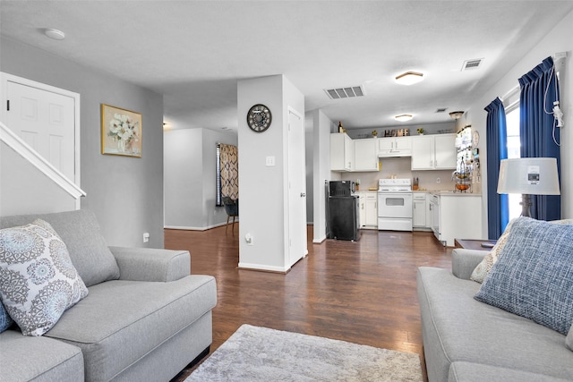 living area with dark wood-style flooring, visible vents, and baseboards