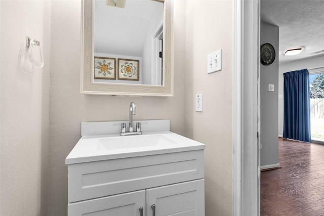 bathroom with visible vents, wood finished floors, vanity, and baseboards