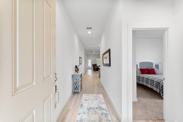 hall featuring light wood-type flooring, baseboards, visible vents, and recessed lighting