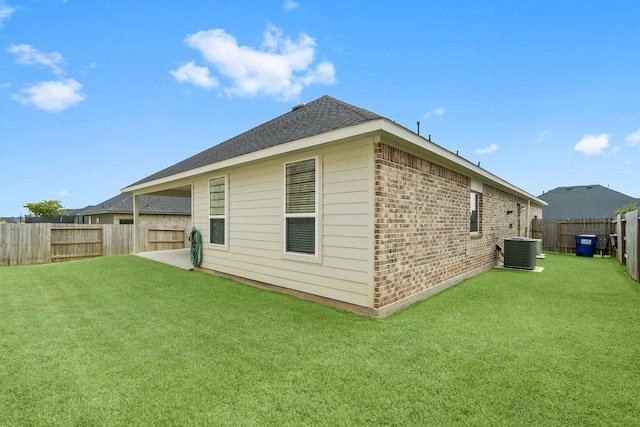 back of house featuring a yard, brick siding, cooling unit, and a fenced backyard