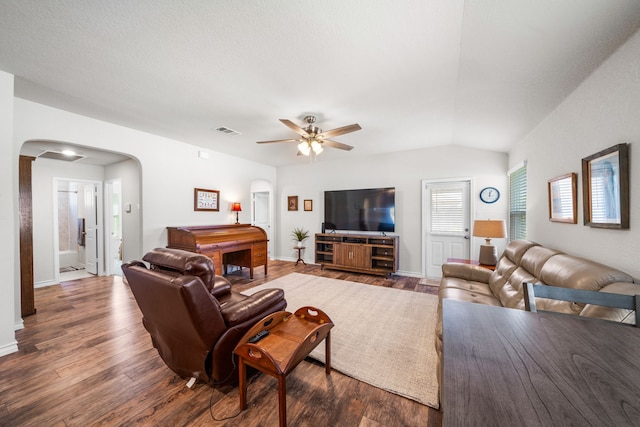 living room with baseboards, visible vents, arched walkways, lofted ceiling, and dark wood-style flooring