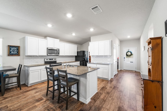 kitchen featuring stainless steel appliances, a kitchen bar, a kitchen island with sink, and white cabinetry