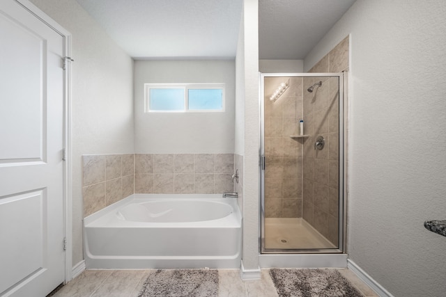 full bath featuring a textured wall, a stall shower, and a garden tub