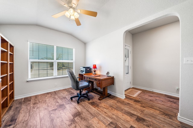 office area with baseboards, arched walkways, a ceiling fan, lofted ceiling, and dark wood-style flooring