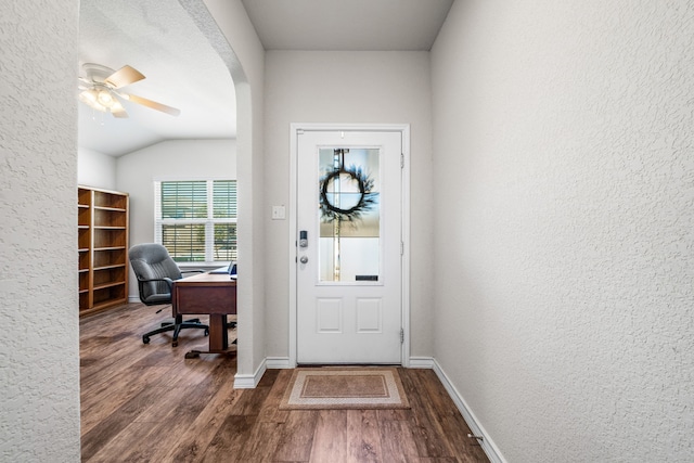 entrance foyer featuring dark wood-style floors, baseboards, arched walkways, and a textured wall