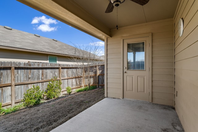 view of exterior entry featuring ceiling fan, a patio area, and fence