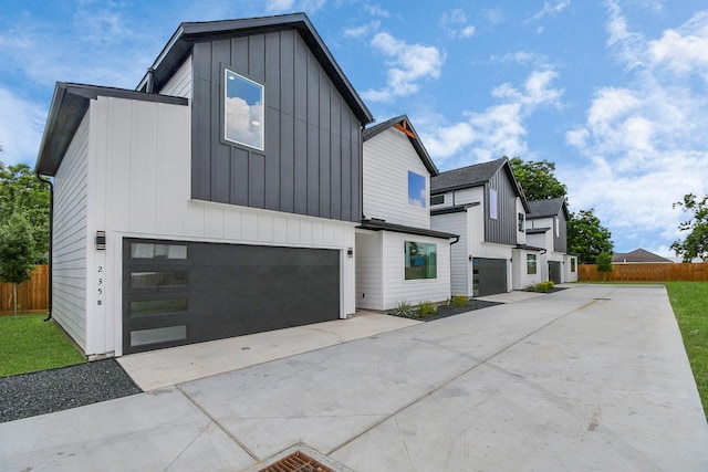 view of property exterior with a garage, driveway, board and batten siding, and fence