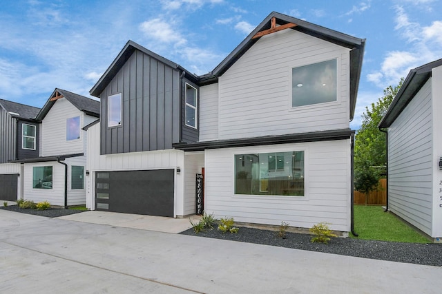 view of front of house featuring a garage, concrete driveway, board and batten siding, and fence