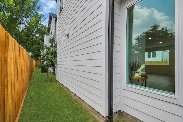 view of side of home featuring central AC unit, a lawn, and fence