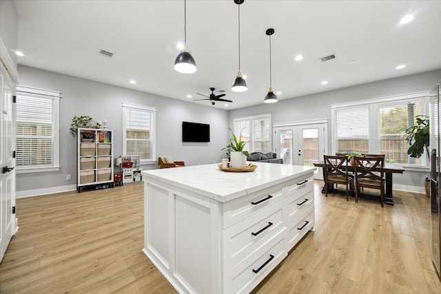 kitchen featuring visible vents, a healthy amount of sunlight, a kitchen island, french doors, and light wood-type flooring