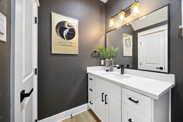 bathroom featuring baseboards, wood finished floors, and vanity