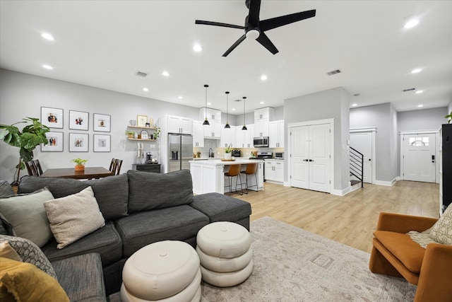 living room featuring recessed lighting, visible vents, a ceiling fan, stairs, and light wood finished floors