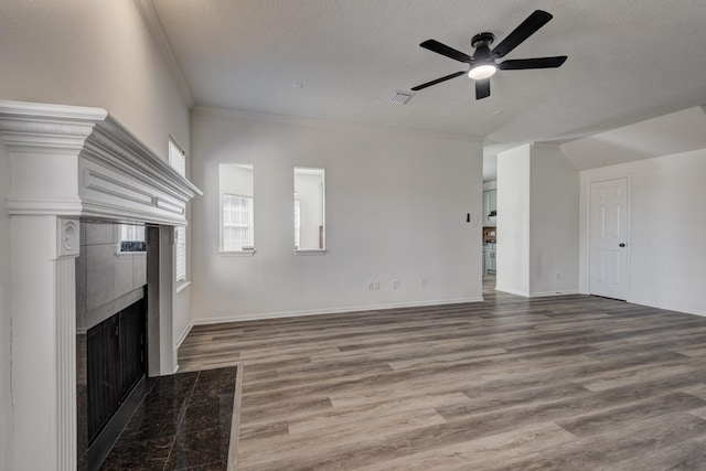 unfurnished living room featuring visible vents, a tile fireplace, ornamental molding, wood finished floors, and a textured ceiling