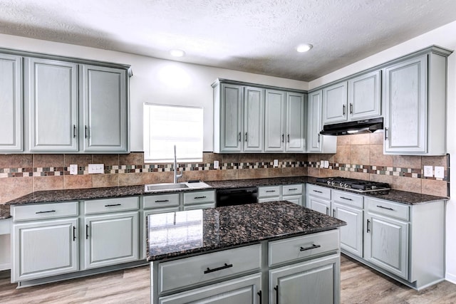 kitchen featuring black dishwasher, stainless steel gas cooktop, gray cabinets, a sink, and under cabinet range hood