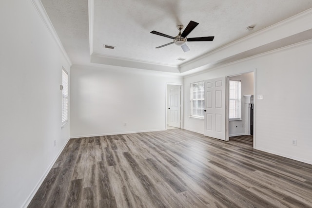 unfurnished bedroom featuring a textured ceiling, a tray ceiling, multiple windows, and visible vents