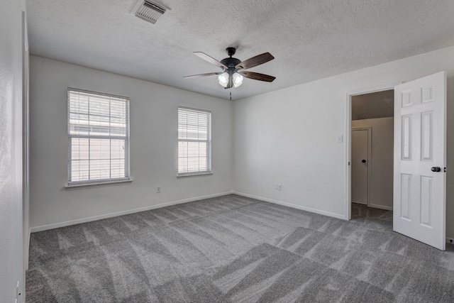 carpeted spare room featuring visible vents, ceiling fan, a textured ceiling, and baseboards