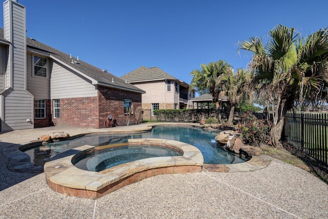 view of swimming pool with a patio area, a pool with connected hot tub, and fence